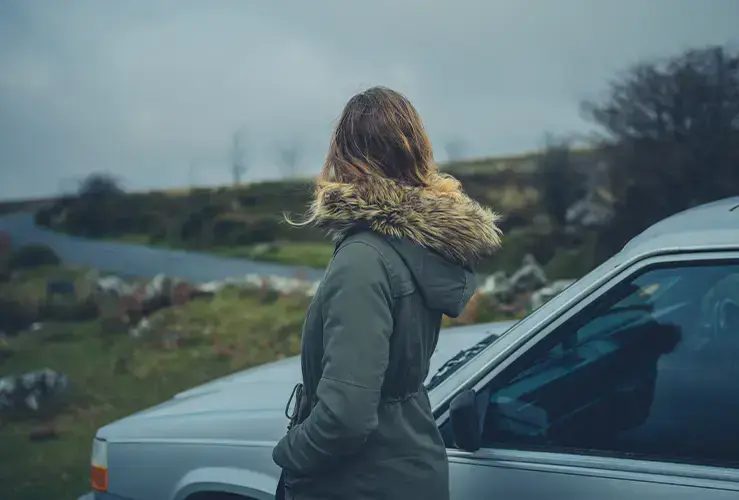 A person standing by the side of a car