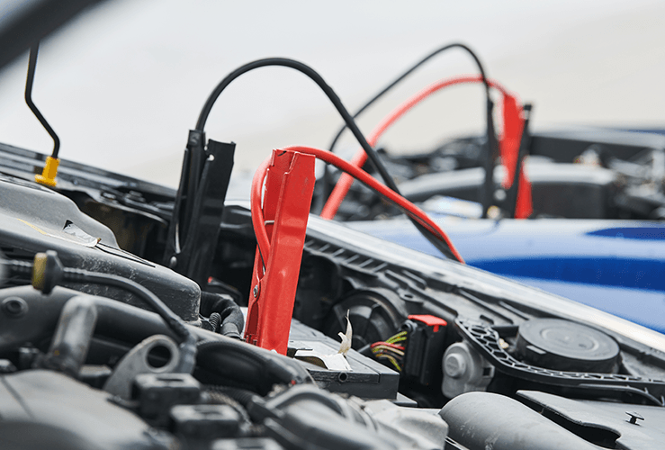 Jump leads connected to a car battery