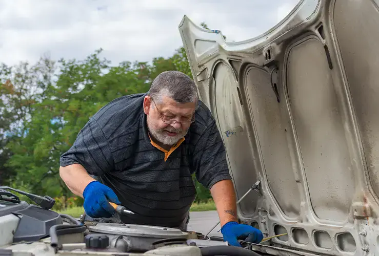 A man repairing a car at the roadside