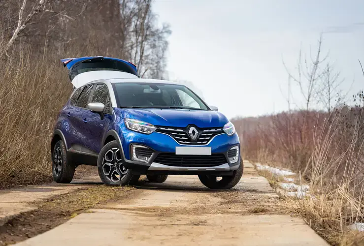 Blue Renault Captur with open boot on a country road