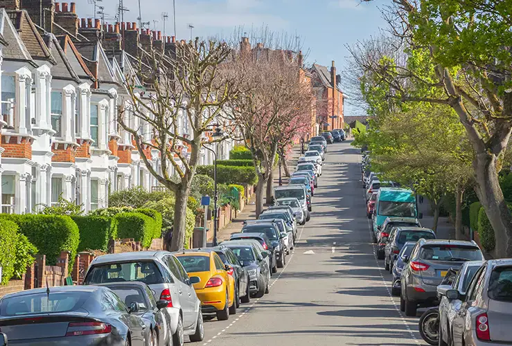 A row of terraced houses with cars parked on the street