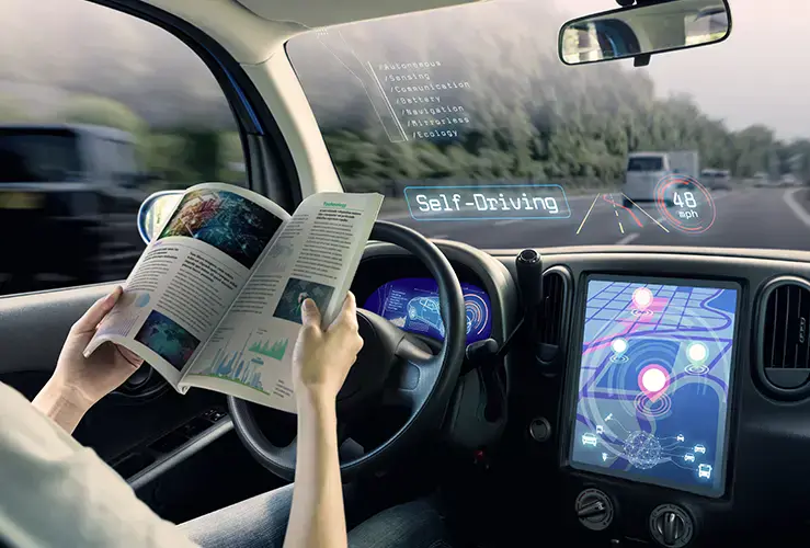 A person reading behind the wheel of a self-driving car
