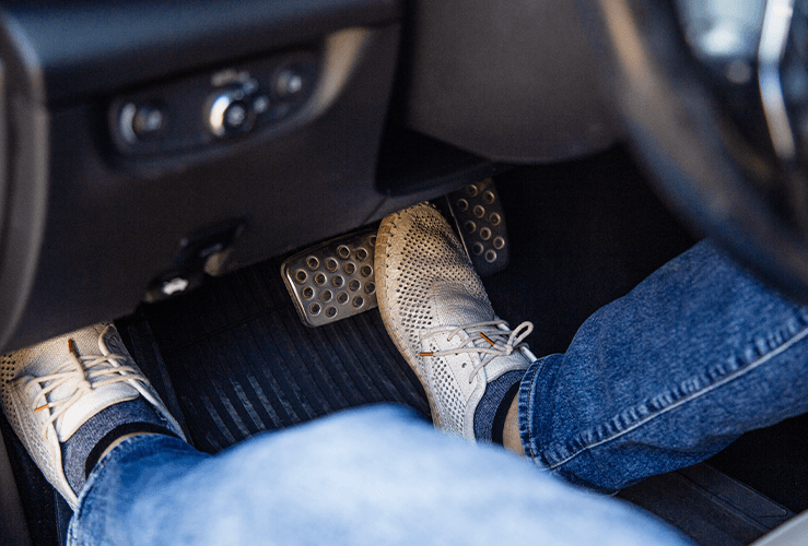 A foot pushing the brake pedal of a car